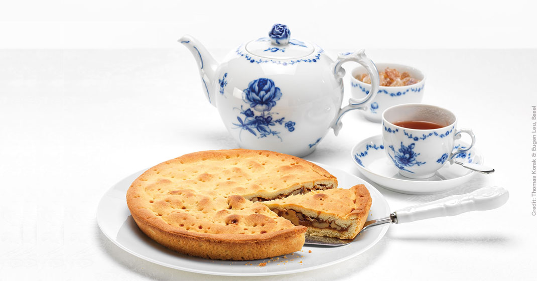 Kuchenstück auf Teller, vor Teekanne und Tasse mit blauem Dekor. Fürstenberg Porzellan.