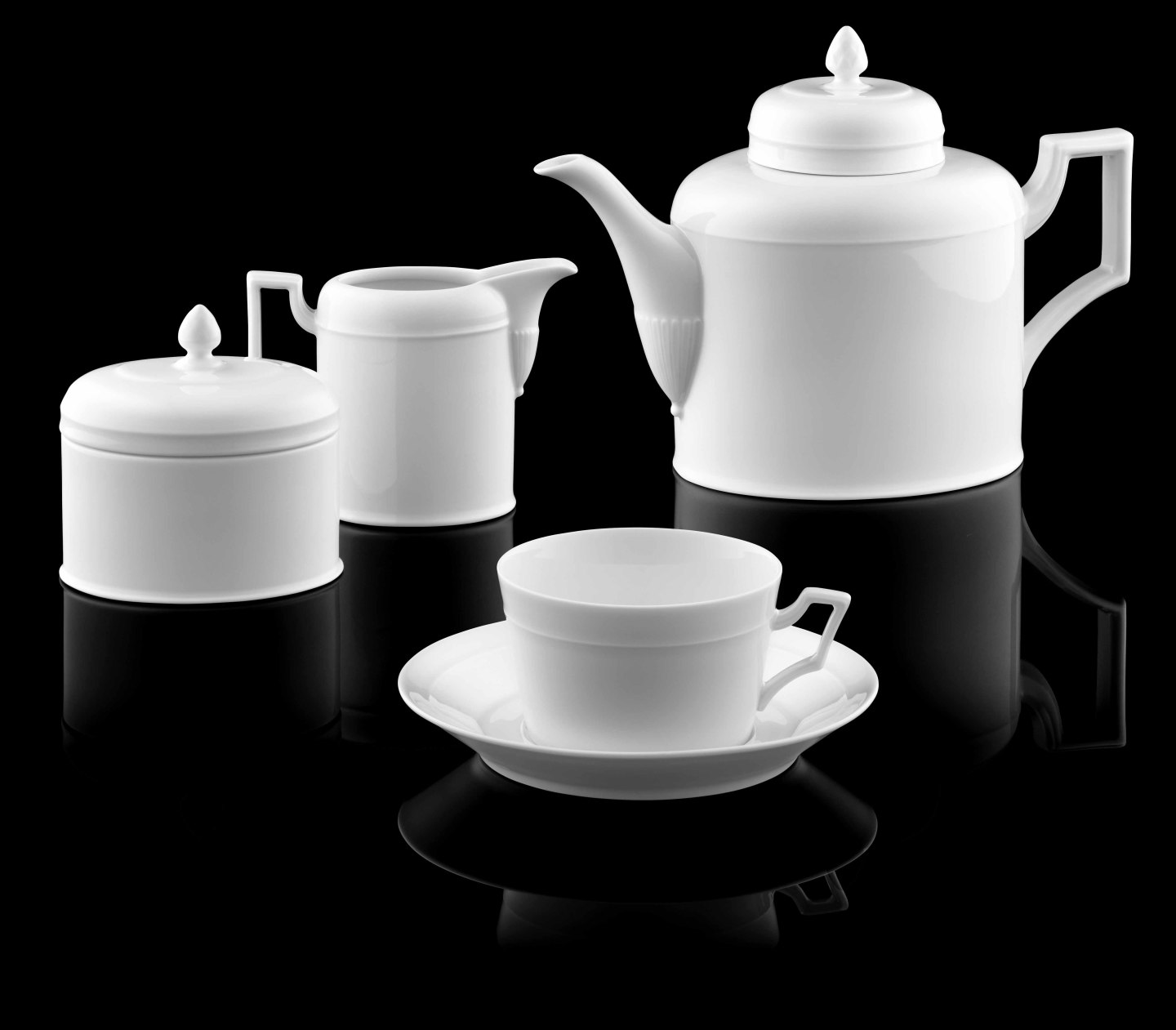 Weiße Porzellan-Teekanne, Tasse, Zuckerdose und Milchkännchen auf schwarzem Hintergrund. Fürstenberg Porzellan.