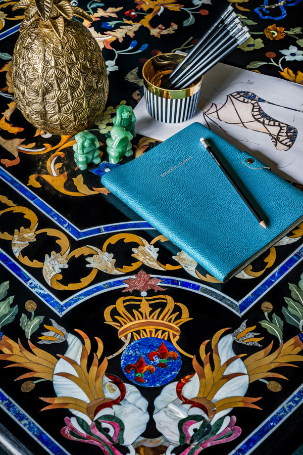 Tisch mit goldenem Ananas, Stifte, Notizbuch in blauer Hülle, dekoratives Muster. Fürstenberg Porzellan.