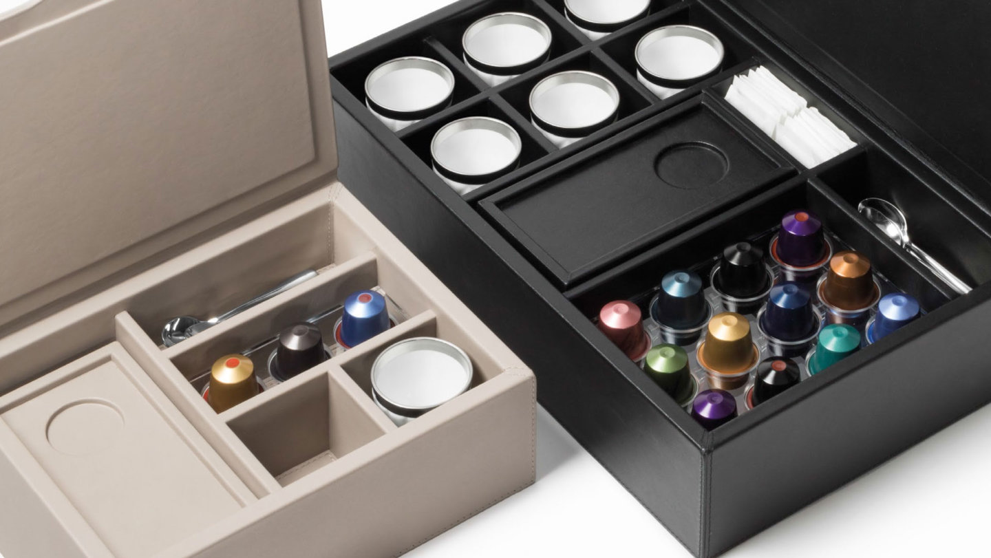 Zwei geöffnete Boxen mit Kaffeekapseln, Tassen, Löffeln und Zuckersticks. Fürstenberg Porzellan.