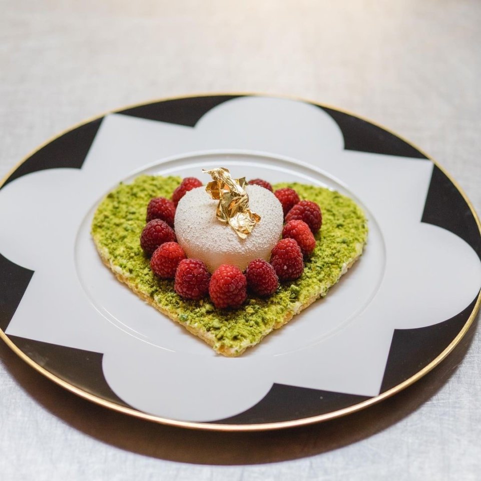 Dessert auf grünem Krokant-Herz mit Himbeeren und goldener Verzierung auf Porzellanteller. Fürstenberg Porzellan.