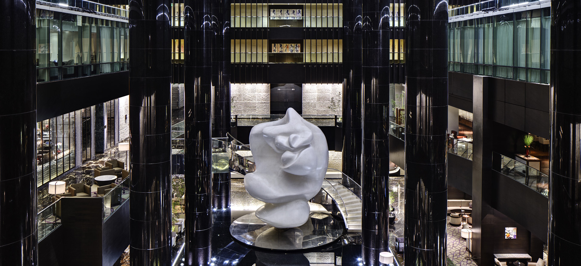 Weiße Skulptur steht in modernem Atrium mit schwarzen Säulen, elegante Atmosphäre. Fürstenberg Porzellan.