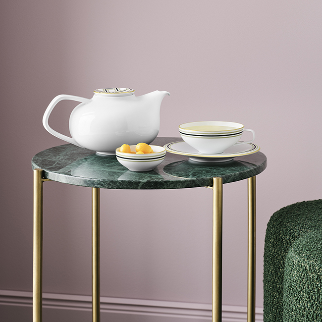 Weiße Teekanne, Tasse, Schale auf grünem Tisch; elegantes Porzellan-Design. Fürstenberg Porzellan.