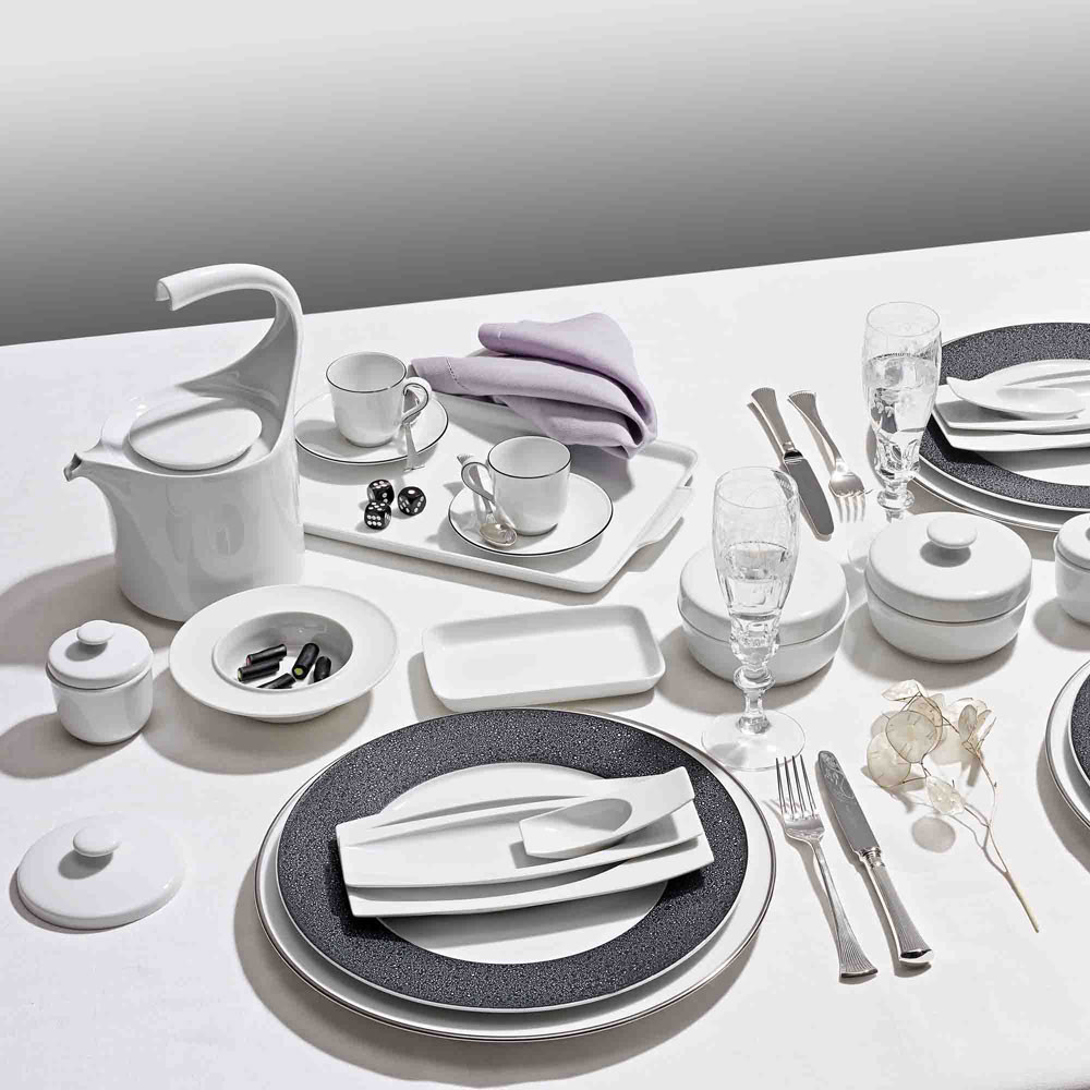 Weißes Porzellan-Geschirr, elegant arrangiert auf einem gedeckten Tisch mit Besteck. Fürstenberg Porzellan.