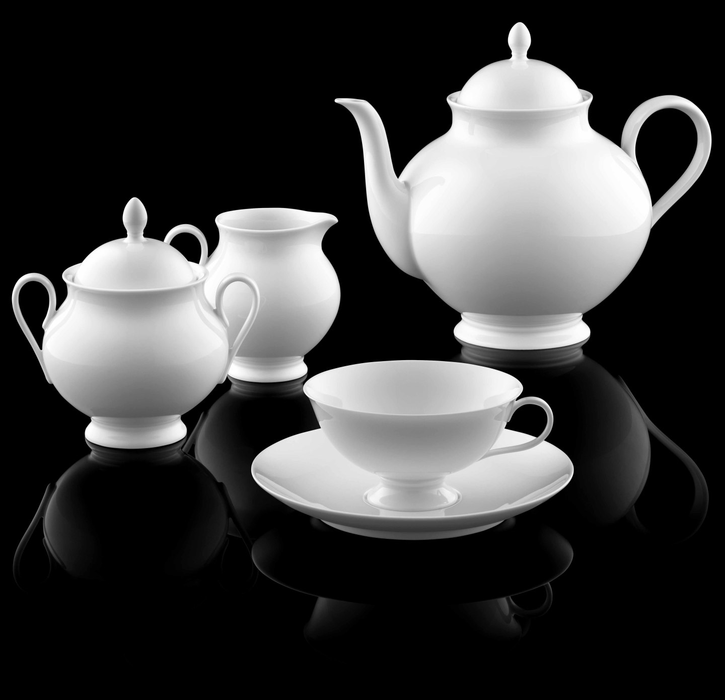 Weiße Porzellan-Teekanne, Zuckerdose, Milchkanne und Tasse auf schwarzem Hintergrund. Fürstenberg Porzellan.