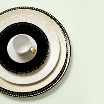 Tassen auf gestapelten Tellern, mit schwarzen und goldenen Details, stilvoll arrangiert. Fürstenberg Porzellan.