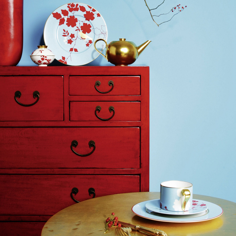 img5_fl2006325700_platzteller Rote Kommode mit Teekanne, Teller, Tasse und Löffel auf goldenem Tisch. Fürstenberg Porzellan.