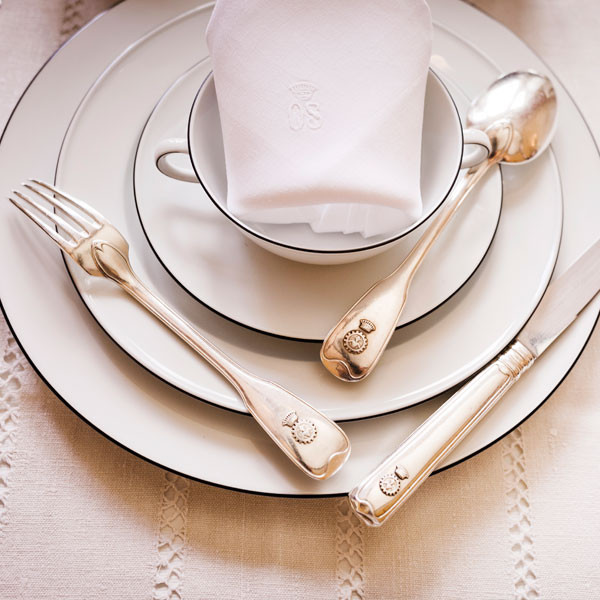 Porzellanteller mit Besteck und Serviette, geschmackvoll auf Tischdecke angeordnet. Fürstenberg Porzellan.
