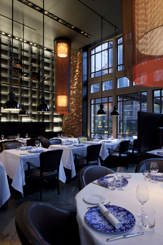 Tische mit blauen Porzellantellern, weißem Geschirr in elegant beleuchtetem Restaurant. Fürstenberg Porzellan.