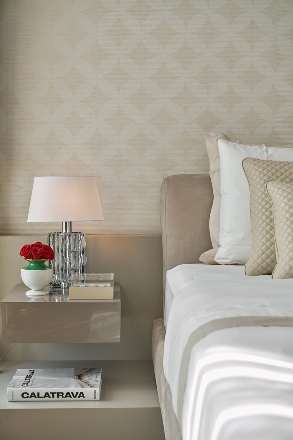 Nachttisch mit Lampe, Blumen, Büchern neben Bett in elegantem Schlafzimmer. Fürstenberg Porzellan.