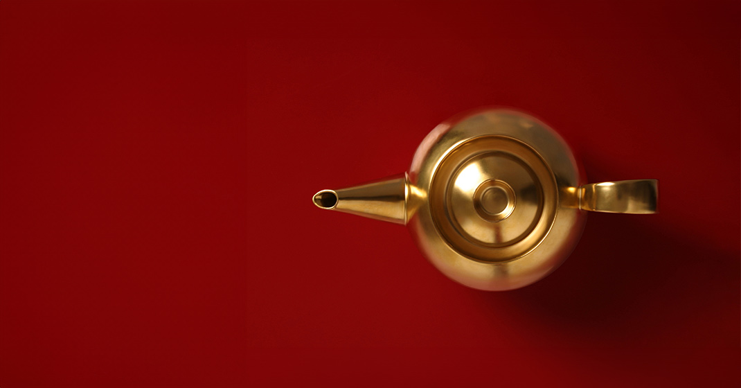 Goldene Teekanne von oben auf rotem Hintergrund, elegant und schlicht. Fürstenberg Porzellan.