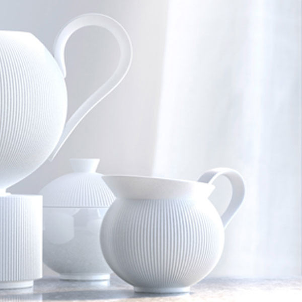 Weiße Porzellan-Kanne, Tassen und Schüssel mit feinem Rillenmuster auf Tisch. Fürstenberg Porzellan.
