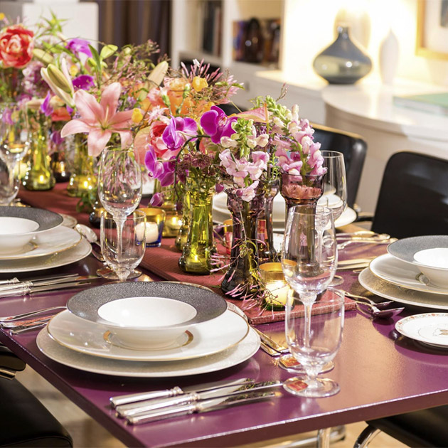 Festlich gedeckter Tisch mit Tellern, Gläsern und Blumenarrangement in Vasen. Fürstenberg Porzellan.