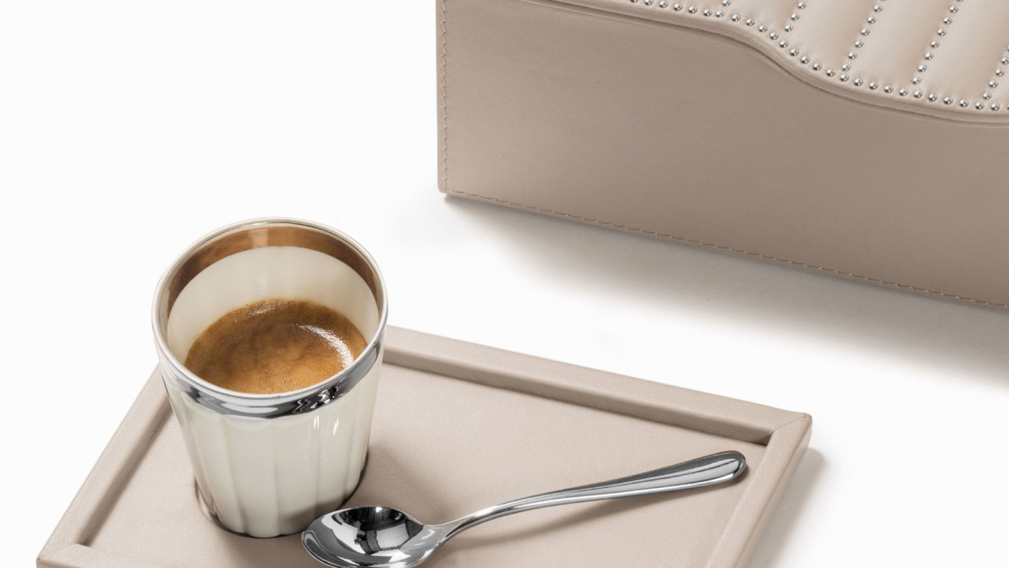 Espressotasse aus Porzellan mit silberner Umrandung steht auf Ledertablett neben Löffel. Fürstenberg Porzellan.