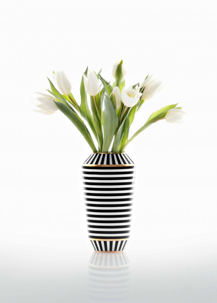 Schwarz-weiß gestreifte Vase hält weiße Tulpen auf spiegelndem Untergrund. Fürstenberg Porzellan.