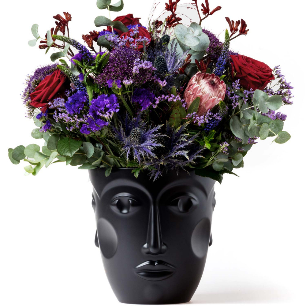 Schwarze Kopfvase hält bunte Blumenarrangement, roter und violetter Akzent. Fürstenberg Porzellan.