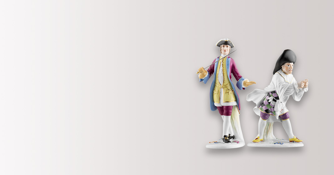Zwei elegante Porzellanfiguren posieren in barocker Kleidung auf hellem Hintergrund. Fürstenberg Porzellan.