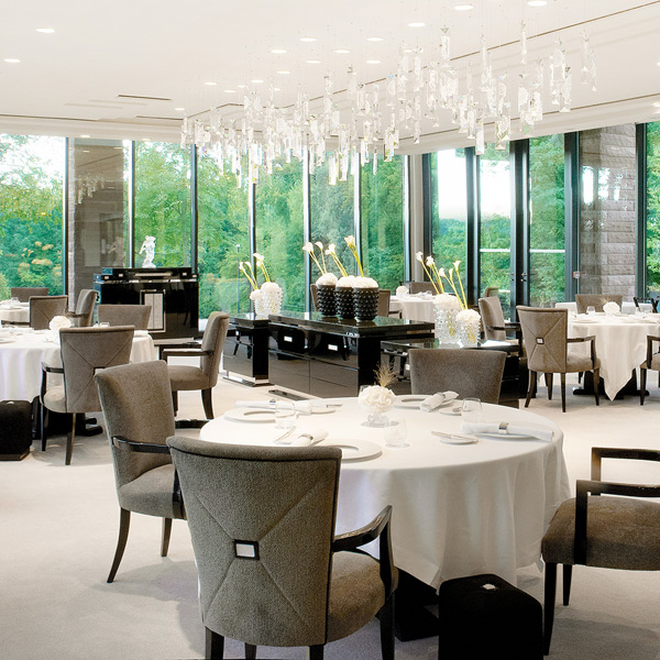 Elegantes Restaurant, modern eingerichtet, mit runden Tischen und großen Fenstern. Fürstenberg Porzellan.