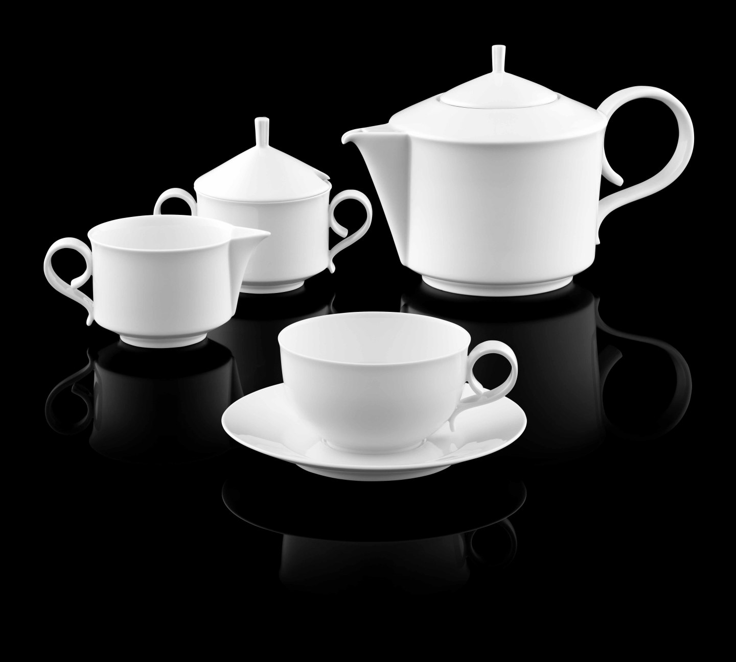 Weiße Teekanne, Zuckerdose, Milchkännchen und Tasse auf schwarzem Hintergrund. Fürstenberg Porzellan.