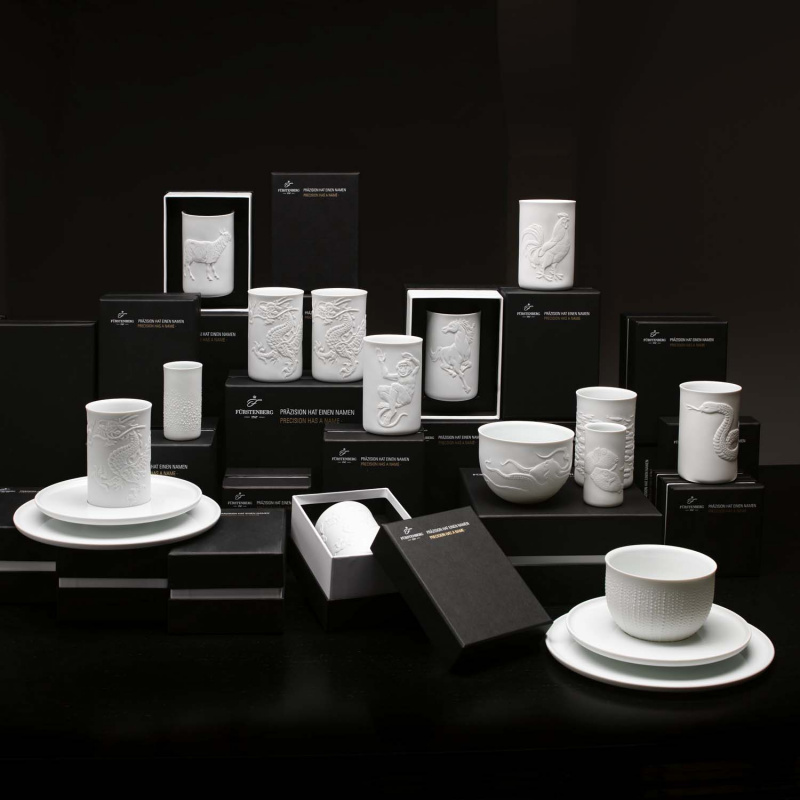 img2_obp8791_1002_becher_doppelwandig__relief_kugelfische_ Weiße Porzellanbecher und -schalen mit Reliefmustern auf schwarzen Boxen. Fürstenberg Porzellan.