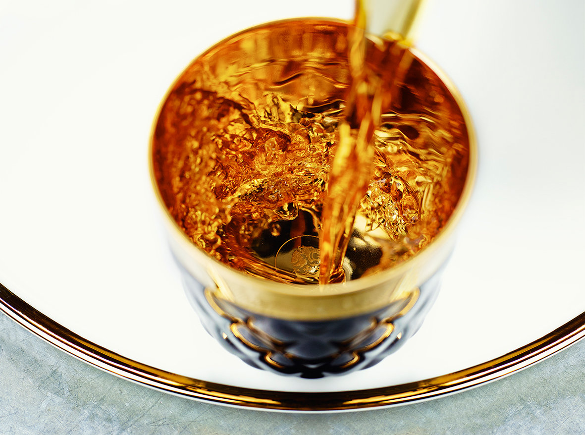 Goldene Flüssigkeit wird in einen verzierte Tasse aus feinem Porzellan gegossen. Fürstenberg Porzellan.