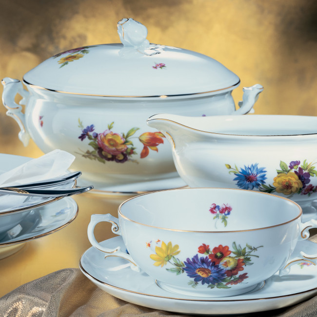 Porzellanservice mit floralen Motiven, goldenen Rändern, steht auf goldenem Hintergrund. Fürstenberg Porzellan.
