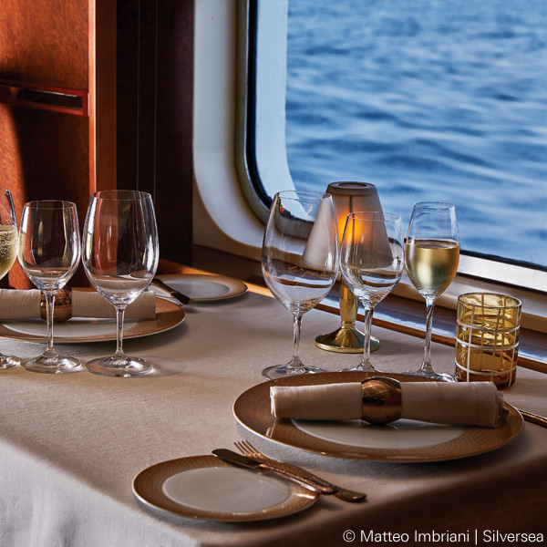 Gedeckter Tisch mit Weingläsern und Kerzen, Ausblick auf Meer durch Fenster. Fürstenberg Porzellan.