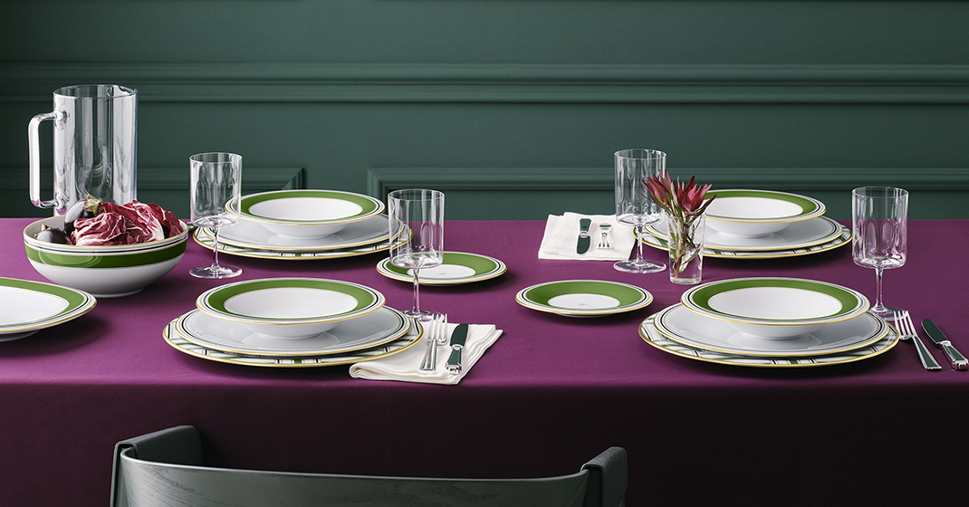 Elegante Tischdekoration mit grün-weißen Tellern, gefüllten Schalen und Kristallgläsern auf violetter Decke. Fürstenberg Porzellan.