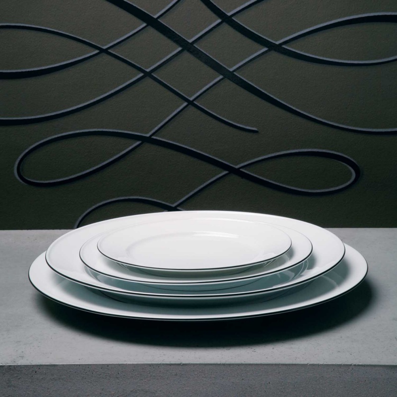 img3_fl_639275003_speiseteller Drei weiße Teller gestapelt auf Tisch vor kunstvoller Wanddekoration. Fürstenberg Porzellan.
