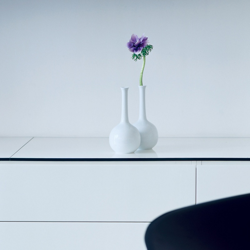 img3_va1462211002_vase Zwei weiße Vasen mit lilafarbener Blume auf weißem Tisch, minimalistisch. Fürstenberg Porzellan.