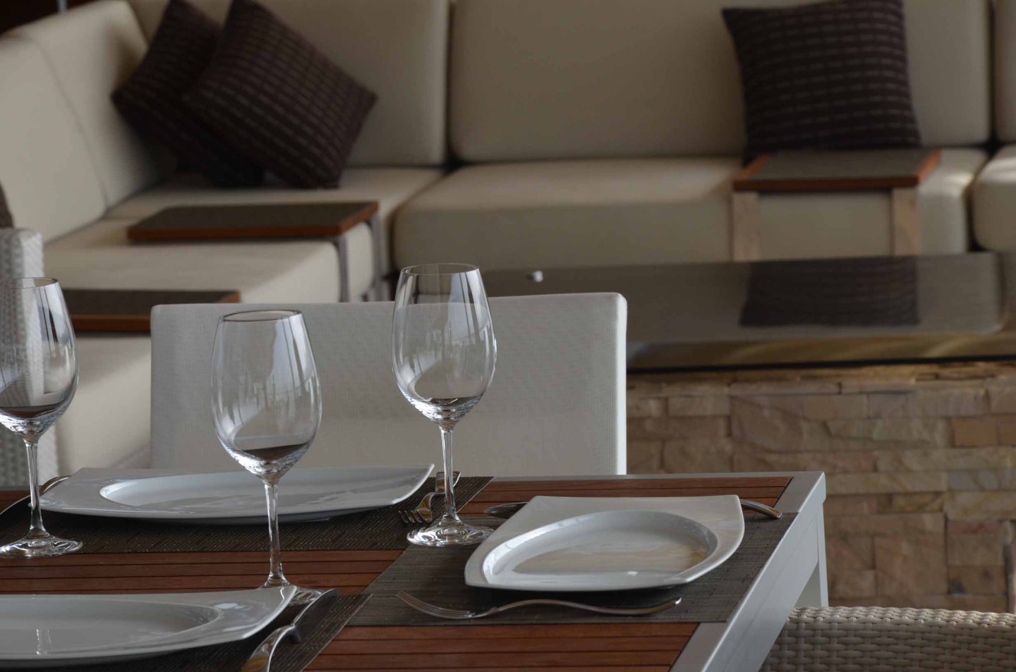 Gedeckter Tisch mit Weingläsern, weißen Tellern, im modernen Wohnzimmer. Fürstenberg Porzellan.