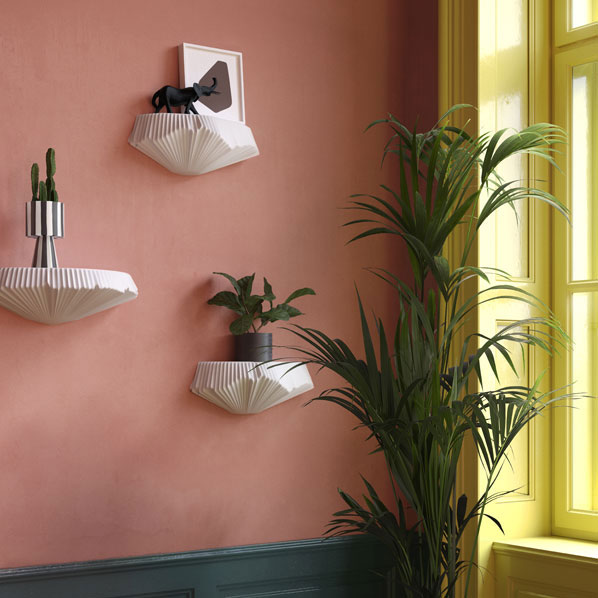 Weiße Wandregale mit Pflanzen und Skulptur an rosa Wand neben gelbem Fenster. Fürstenberg Porzellan.