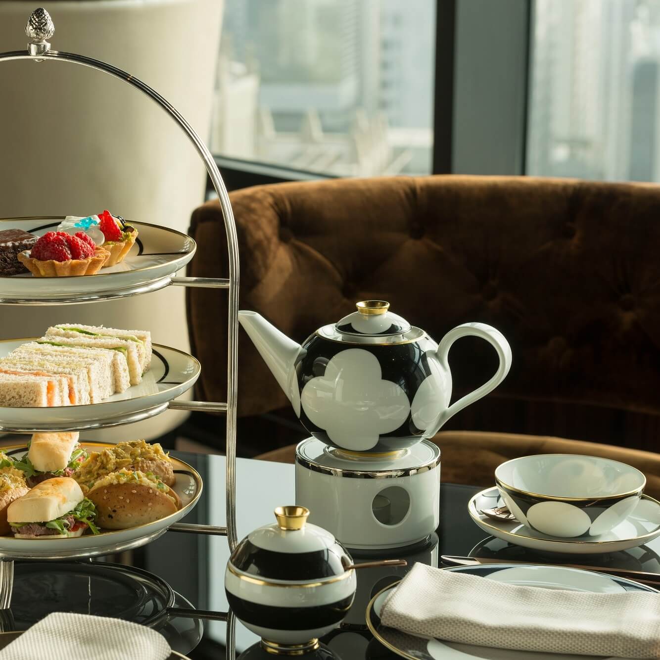 Etageren mit Sandwiches, Gebäck; Teekanne daneben auf Tisch, luxuriöse Umgebung. Fürstenberg Porzellan.