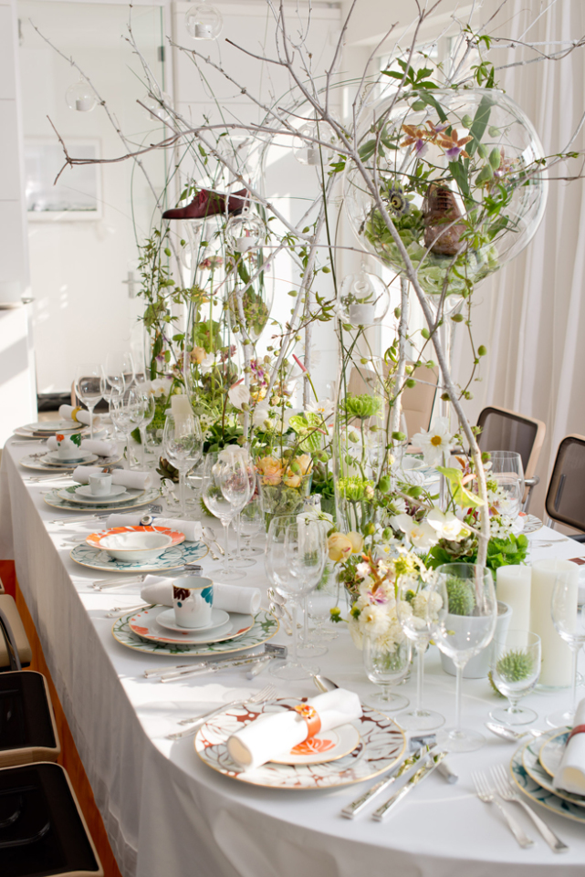 Festlich gedeckter Tisch mit Geschirr, Blumenarrangements und hängenden Glasdekorationen. Fürstenberg Porzellan.