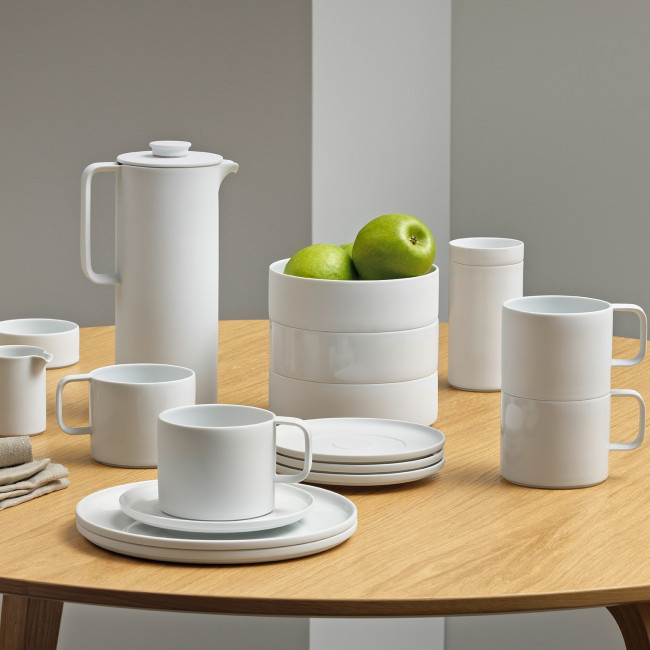 Weißes Porzellan-Geschirr mit grünen Äpfeln auf hölzernem Tisch arrangiert. Fürstenberg Porzellan.