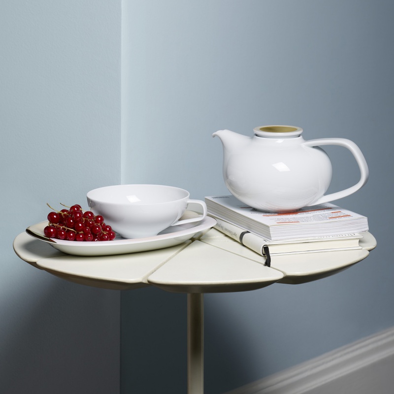 img4_FluenMotiv01089V8 Teekanne steht auf Büchern, daneben Schale mit Johannisbeeren auf kleinem Tisch. Fürstenberg Porzellan.