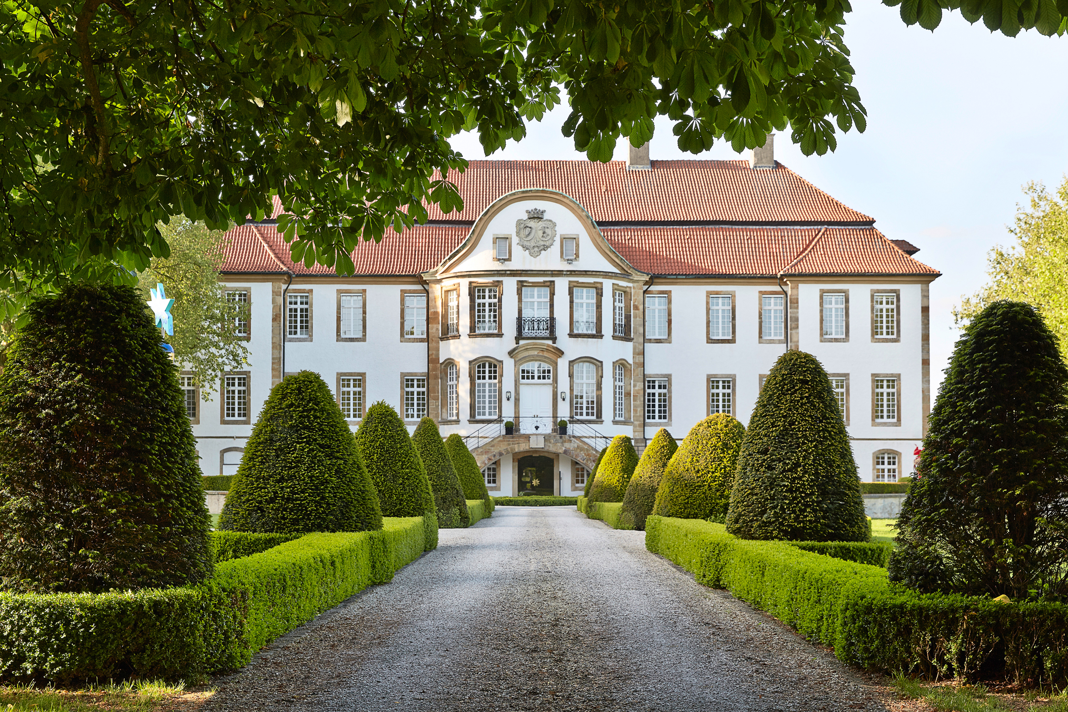 Schloss mit rotem Dach, symmetrischen Fenstern, umrahmt von beschnittener Gartenlandschaft. Fürstenberg Porzellan.