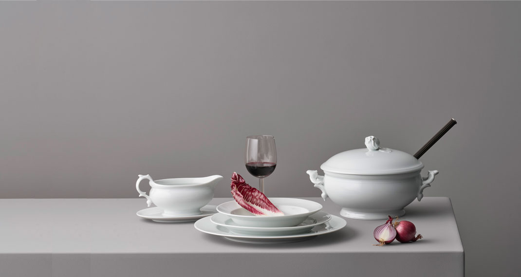 Weiße Porzellanservierschüssel und Teller mit Radicchio, Rotweinglas und Zwiebeln. Fürstenberg Porzellan.