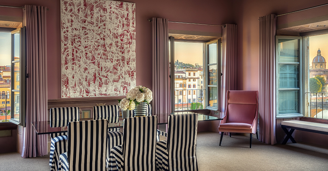 Esszimmer, gestreifte Stühle, Glastisch, rosa Wände, große Fenster, florales Bild. Fürstenberg Porzellan.