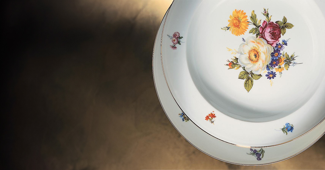 Teller mit buntem Blumenmuster, auf dunklem Hintergrund liegend. Fürstenberg Porzellan.