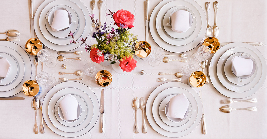 Gedeckter Tisch mit Porzellan-Set, goldenen Gläsern, Blumen, elegantem Geschirr, Besteck. Fürstenberg Porzellan.