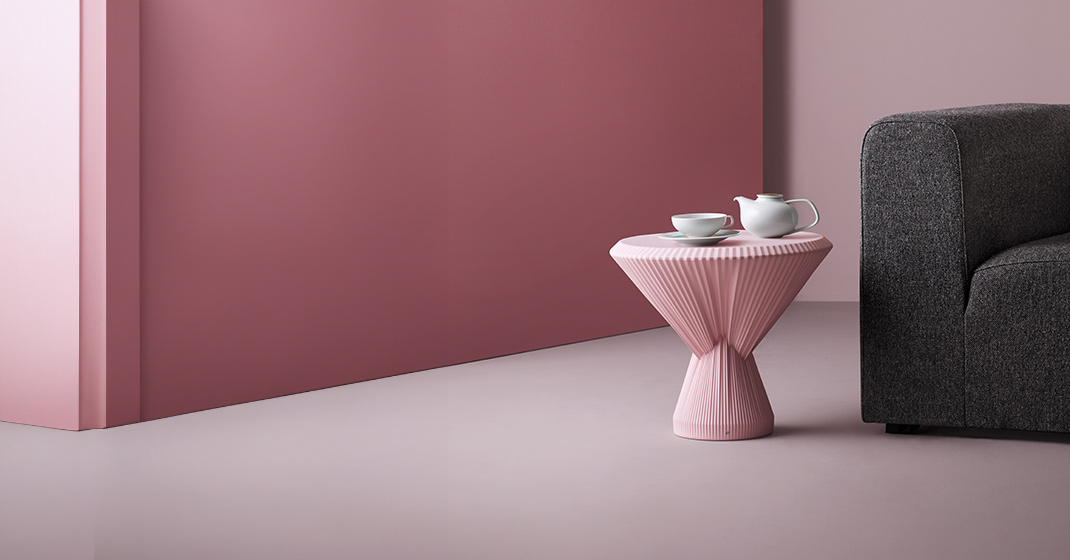 Rosa Beistelltisch mit Teeservice neben grauem Sofa in modernem Raum. Fürstenberg Porzellan.