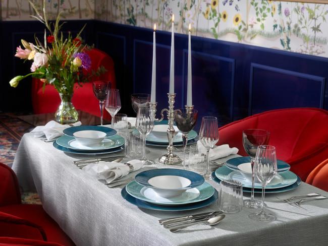Eleganter Tisch gedeckt mit Porzellangeschirr und Kerzenleuchtern, umgeben von roten Stühlen. Fürstenberg Porzellan.