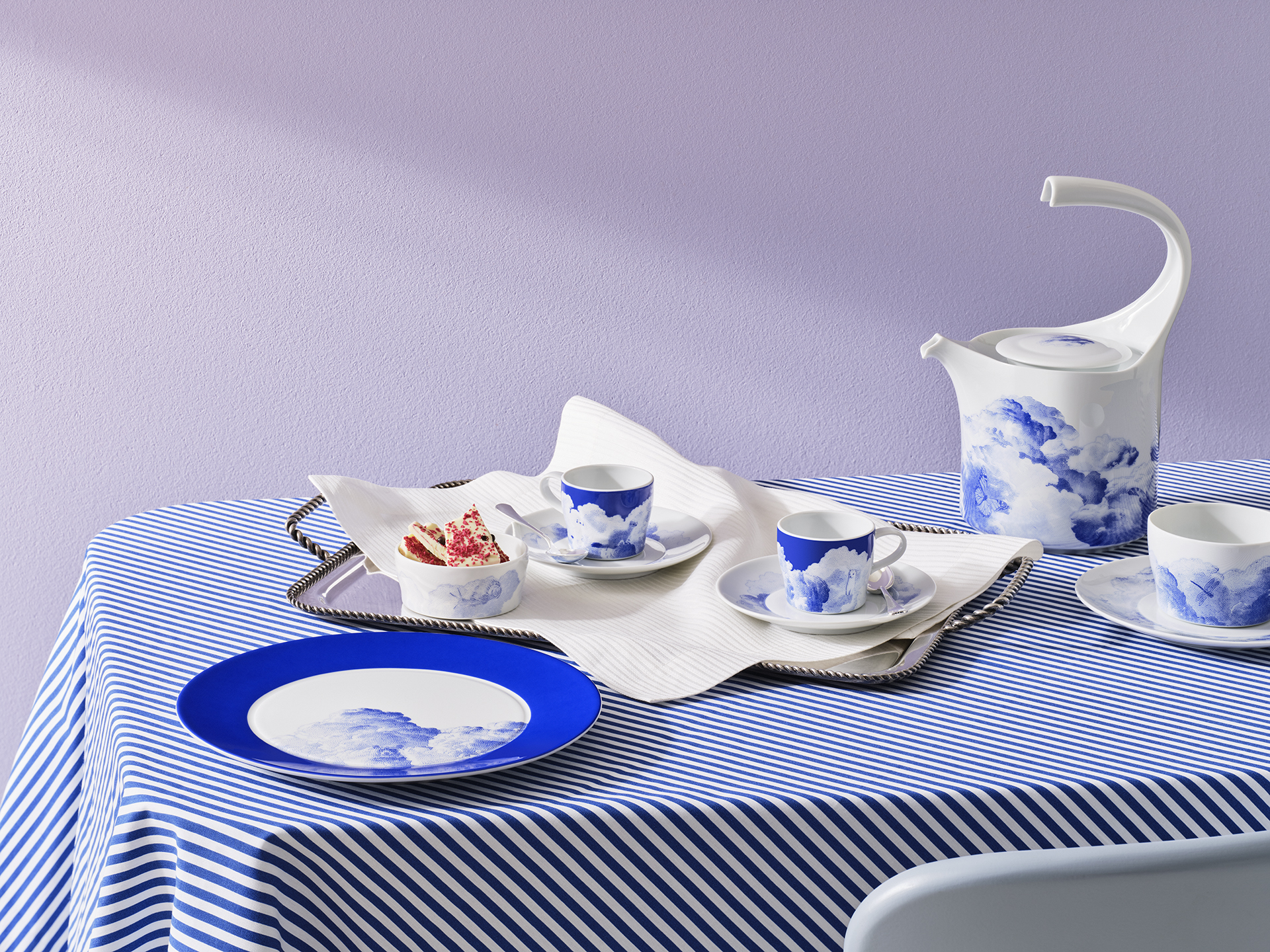 Porzellan-Geschirr mit Himmel-Motiven auf gestreiftem Tischtuch, bestehend aus Tassen und Kanne. Fürstenberg Porzellan.