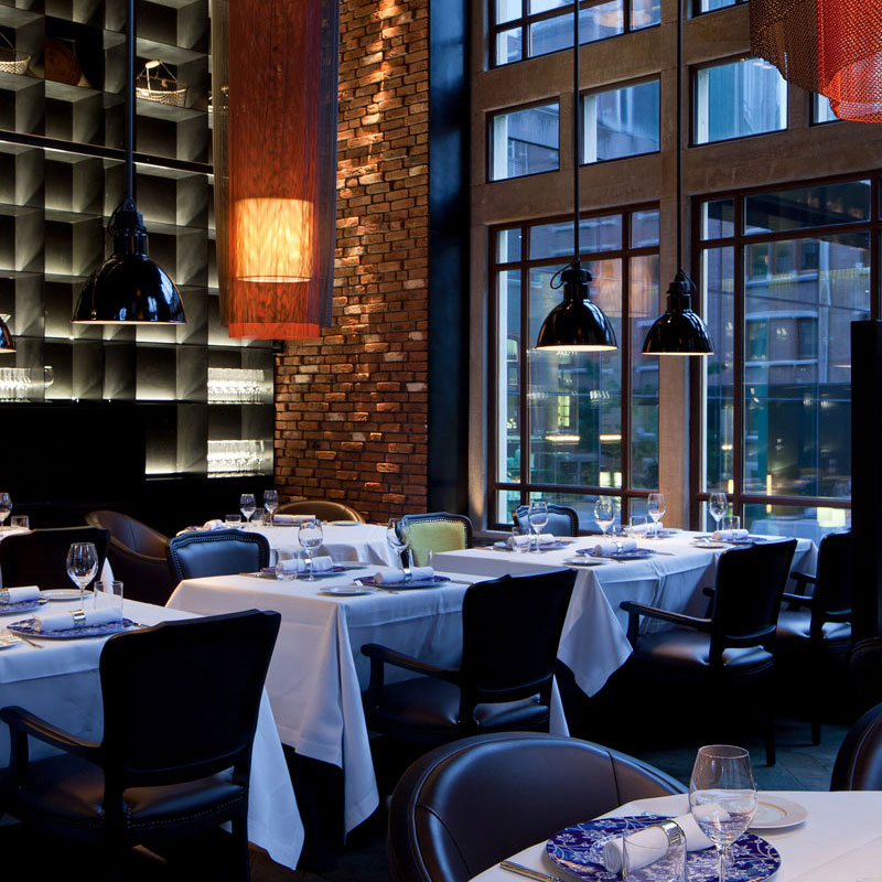 Tische mit weißen Tischdecken in elegantem Restaurant, umgeben von großen Fenstern. Fürstenberg Porzellan.