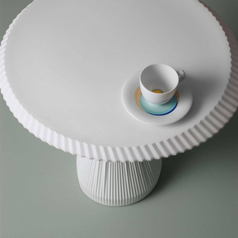 img4_btp888421000_plisago_42_beistelltisch_weiss Weiße Tasse auf geriffeltem Tisch mit bunter Untertasse. Fürstenberg Porzellan.
