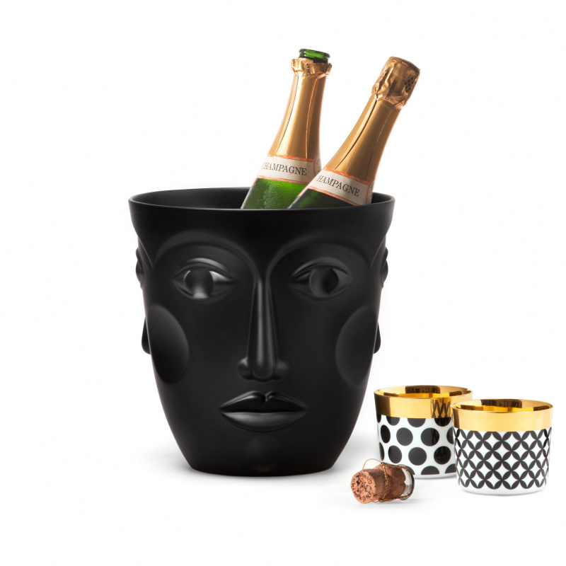 img2_ck1857256102_sektkuehler_faces__satin_black Schwarzer Eiskübel mit Gesichtsmotiv hält zwei Champagnerflaschen, daneben Tassen. Fürstenberg Porzellan.