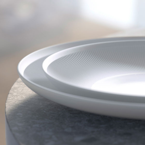 Weiße Porzellanschale liegt auf grauem Tisch, feine Linienstruktur sichtbar. Fürstenberg Porzellan.