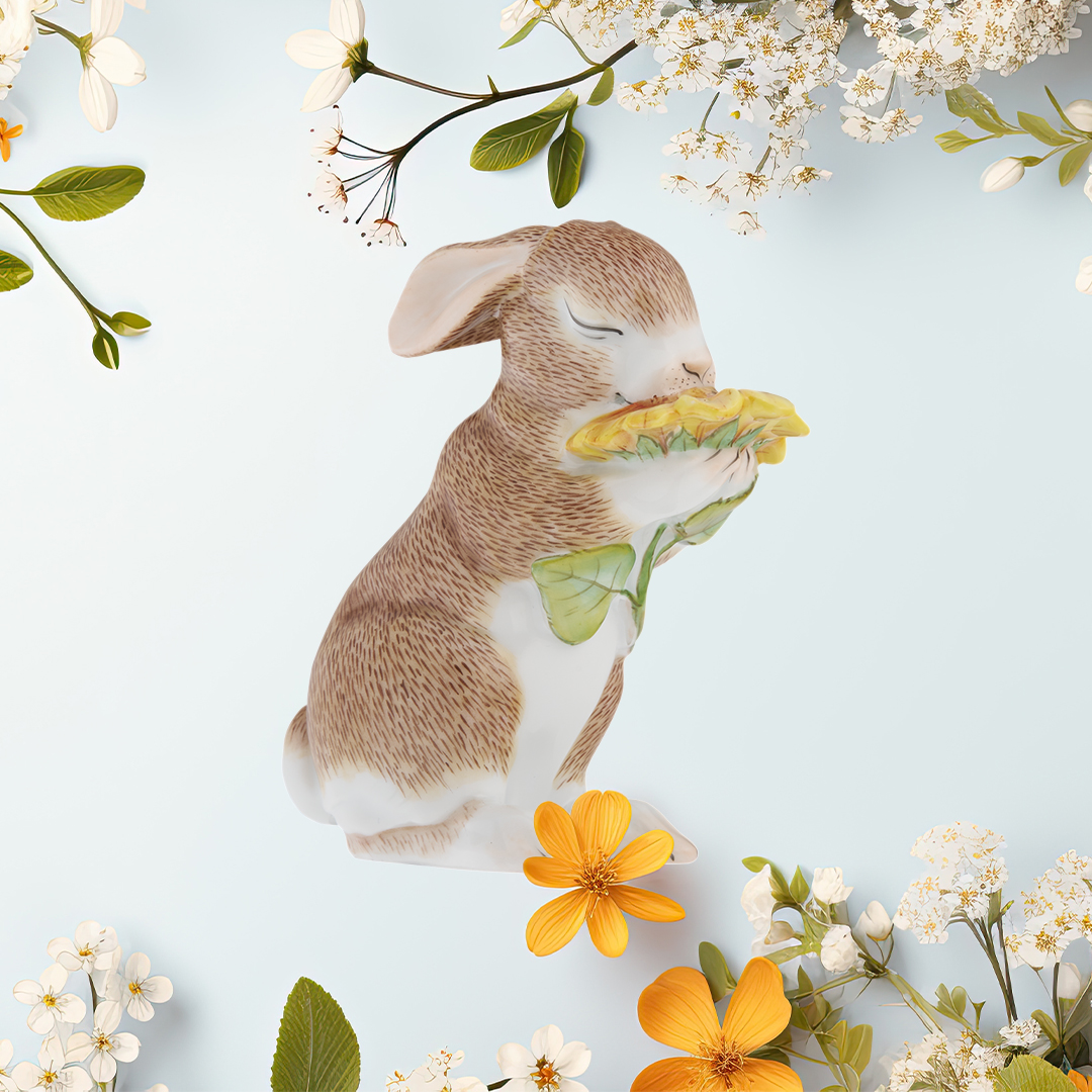 Kaninchenfigur hält Blume, umgeben von Frühlingsblüten und Blättern. Fürstenberg Porzellan.