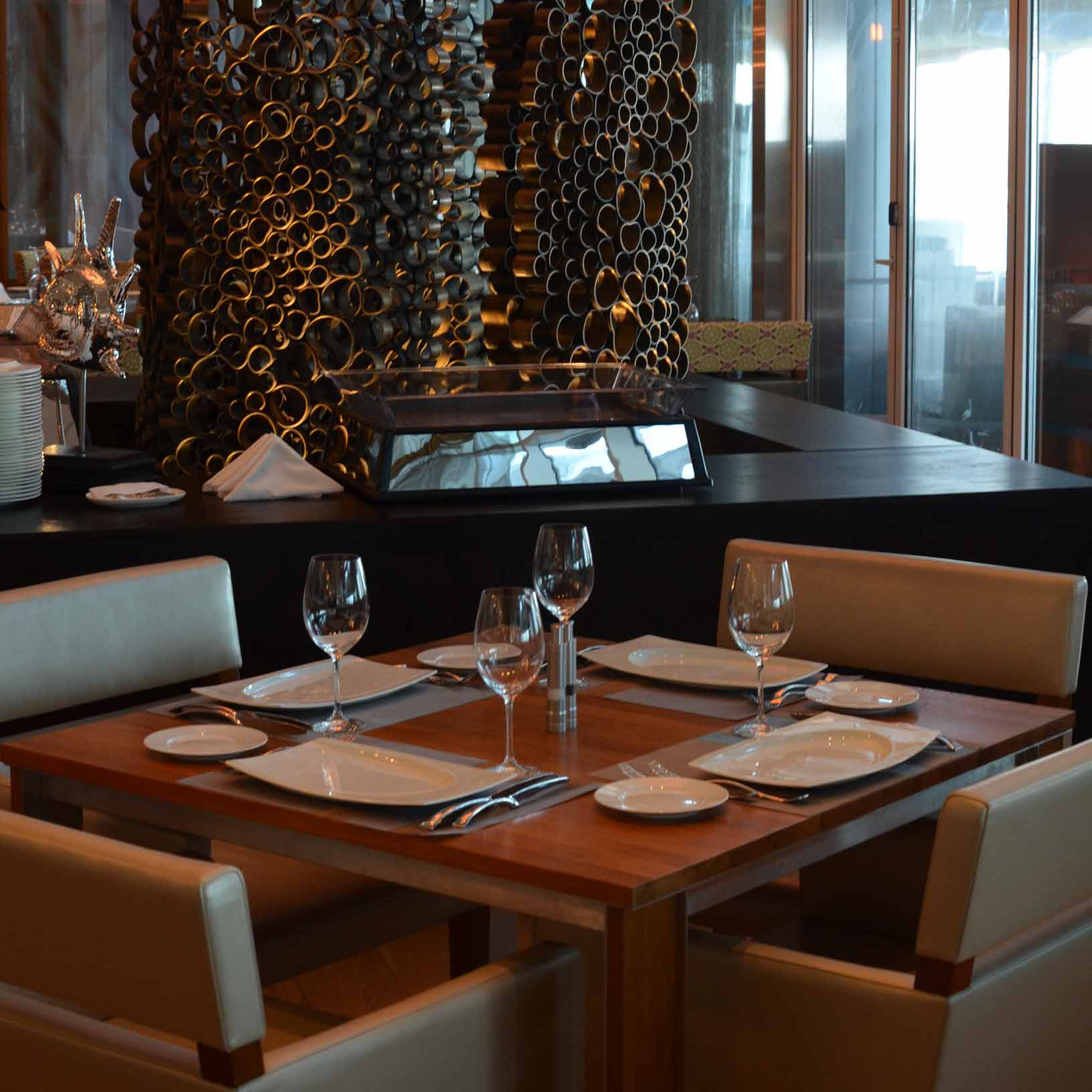 Restauranttisch, gedeckt mit Gläsern und Tellern, moderne Dekoration im Hintergrund. Fürstenberg Porzellan.